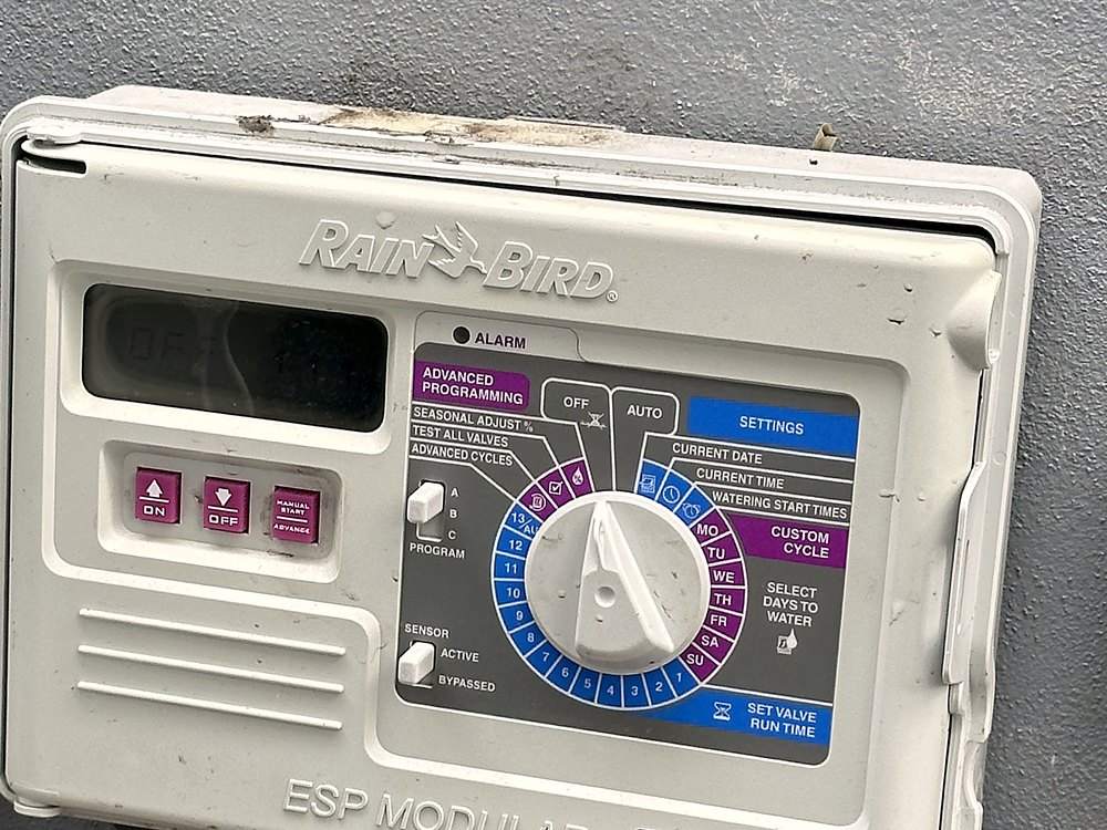 A Rain Bird ESP Modular irrigation controller with an LCD display and dial, mounted outdoors