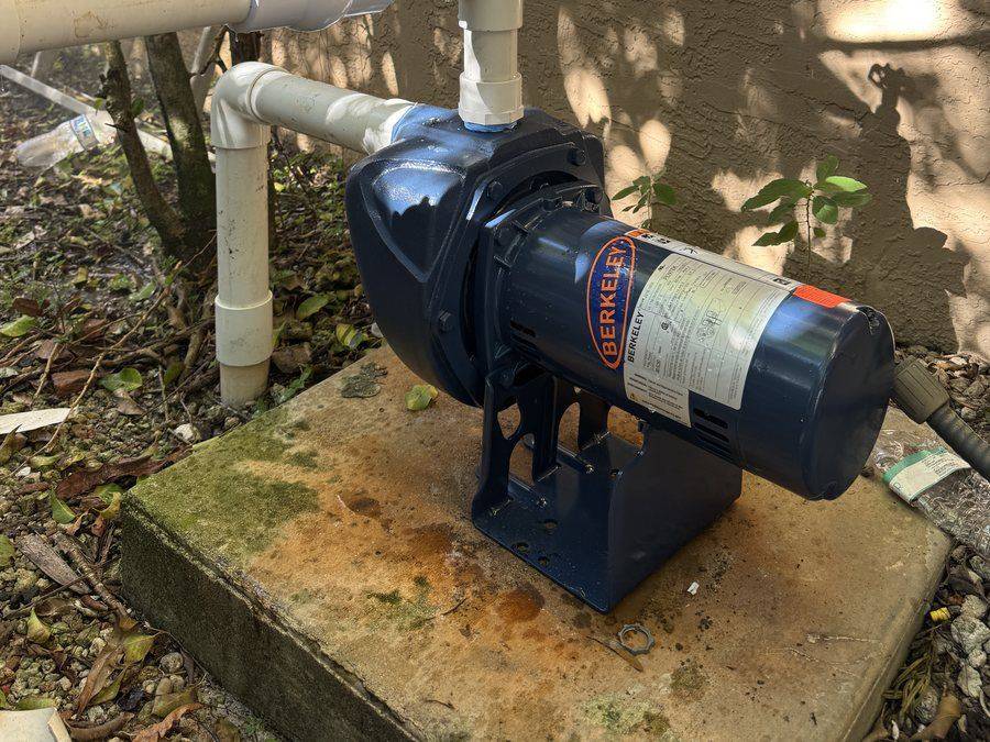 A cast-iron well pump on a concrete pad beside a house